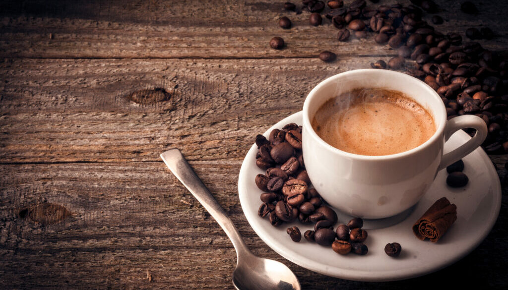 Cup of coffee on wooden table with cinnamon