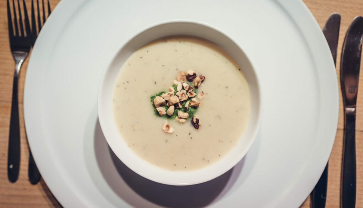 Sunchoke soup with roasted peanuts in white bowl