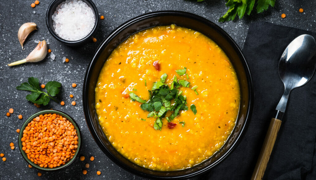 Red lentil soup on black top view.