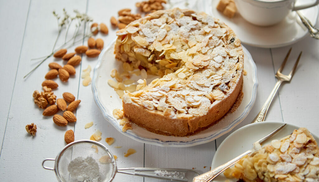 Whole delicious apple cake with almonds served on wooden table