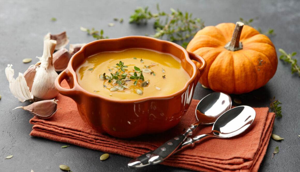 Pumpkin soup with thyme and pumpkin seeds on black background