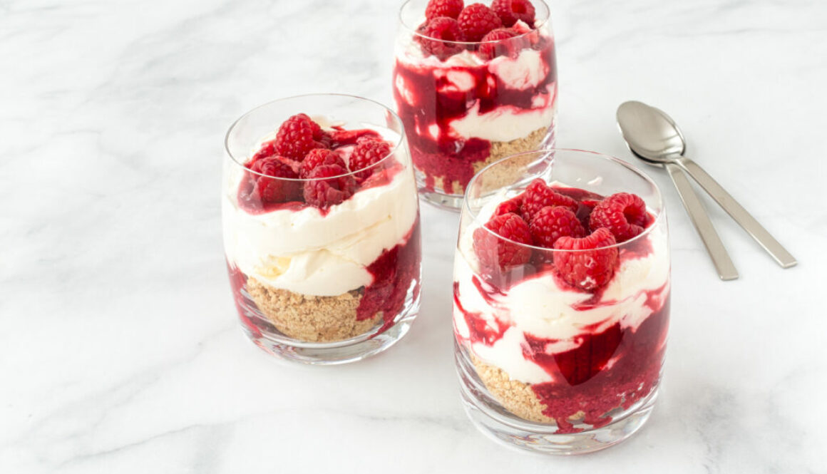 Raspberry Cheesecake Dessert in Glasses on White Marble